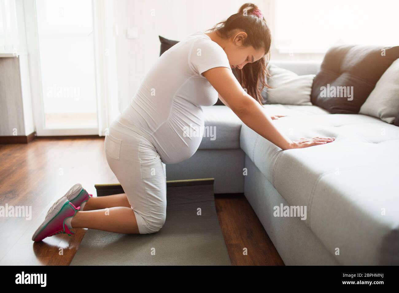 Schwangere Frau beim Training zu Hause mit einem Sofa. Stockfoto