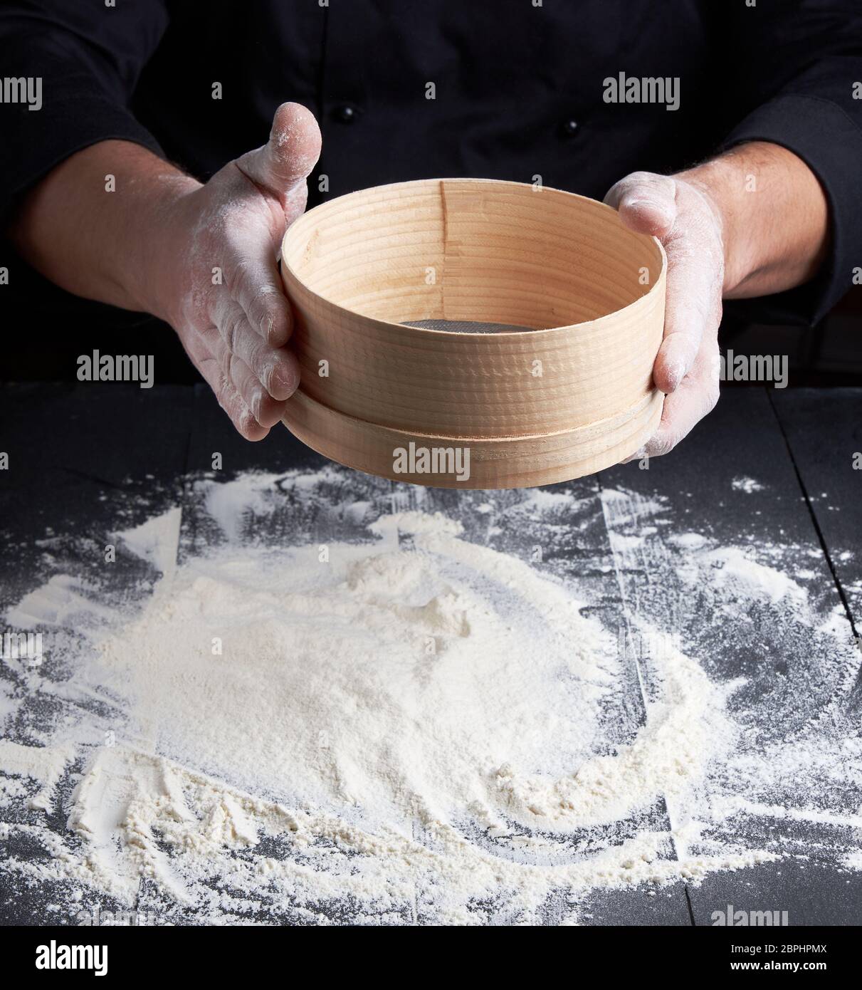 Man siebt weißes Mehl durch ein Sieb, schwarzer Hintergrund Stockfotografie  - Alamy