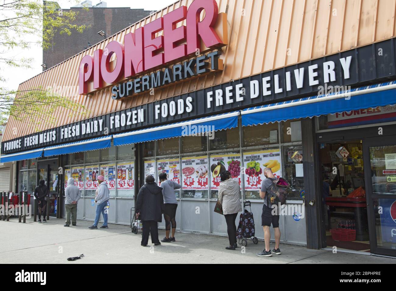Lebensmitteleinkäufer, die während der Covid-19-Pandemie auf den Pioneer Market im Viertel Flatbush in Brooklyn New York warten, distanzieren sich von der Gesellschaft Stockfoto