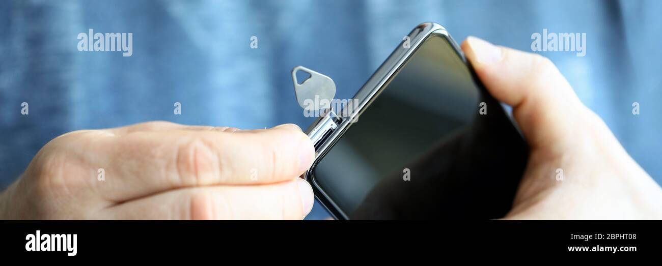 Man zieht SIM-Kartensteckplatz für neues Telefon mit Stift heraus Stockfoto