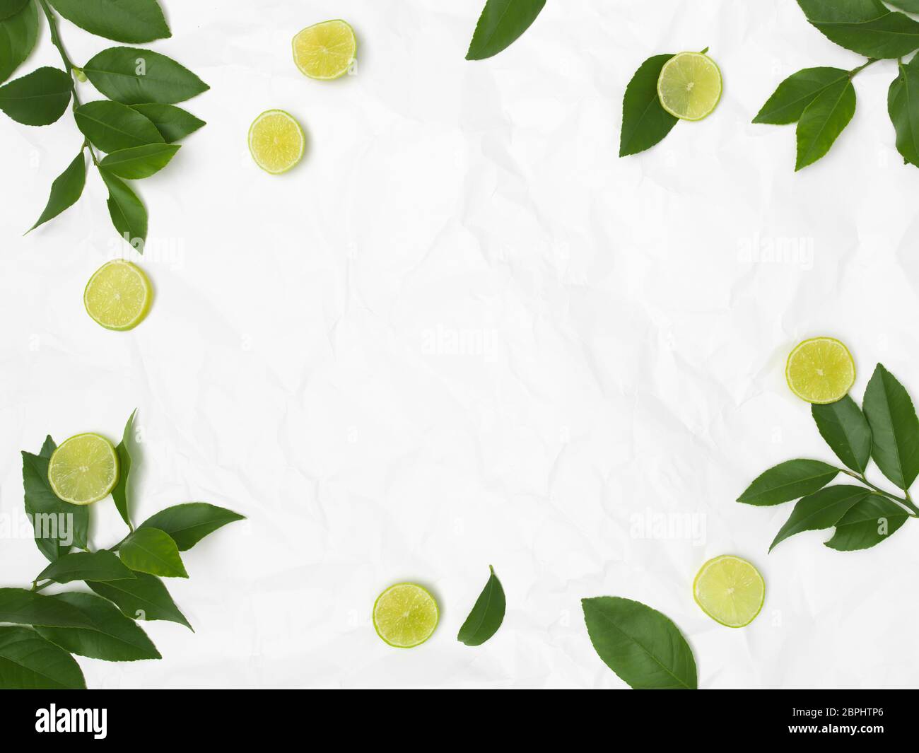 Limonen und grüne Blätter auf weißem zerknitterte Hintergrund Stockfoto