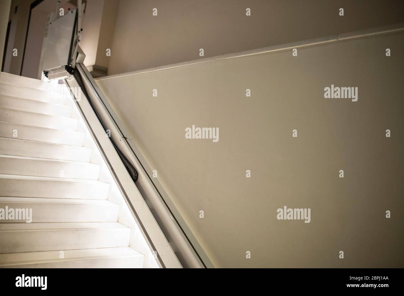 Treppenlift für Behinderte und ältere Menschen, um Treppen mit beleuchteten Stufen zu klettern. Selektiver Fokus Stockfoto
