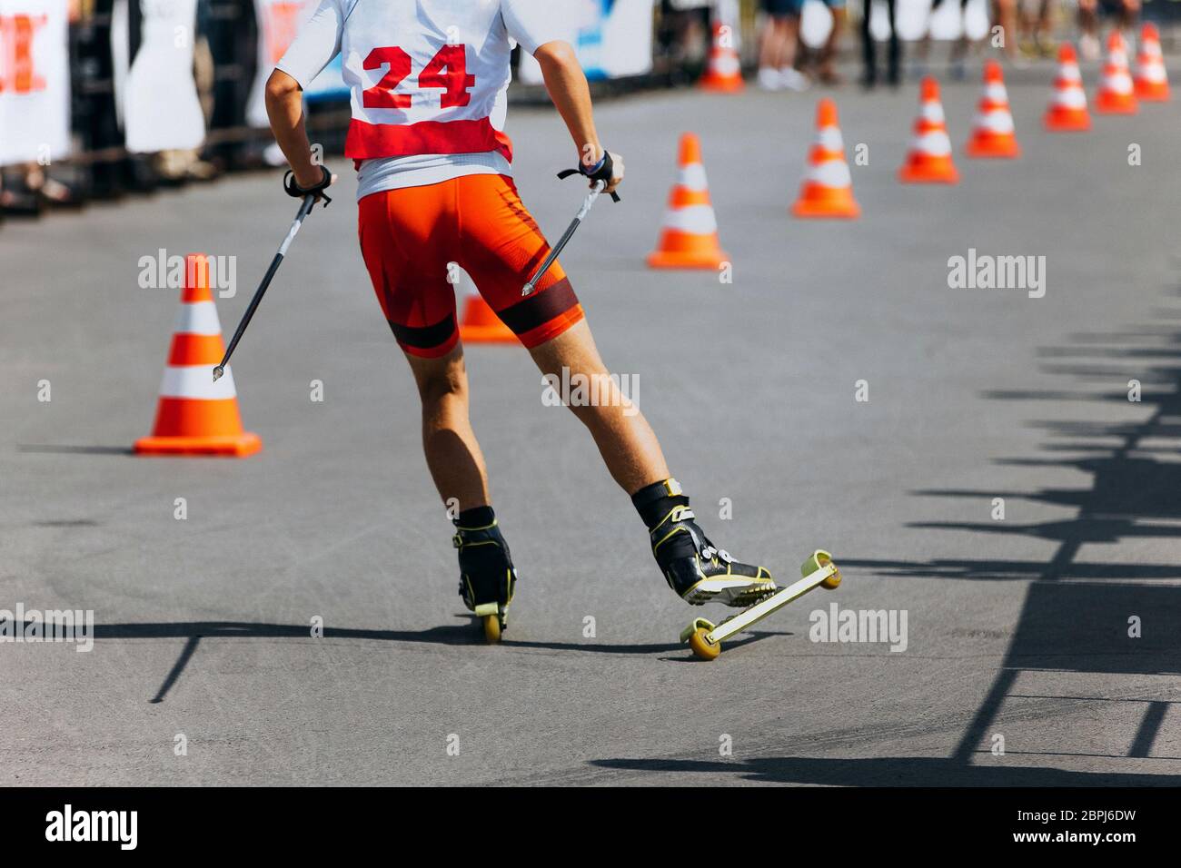 Zurück Sportler Skifahrer Roller Skirennen auf Asphalt mit Verkehrskegel Stockfoto