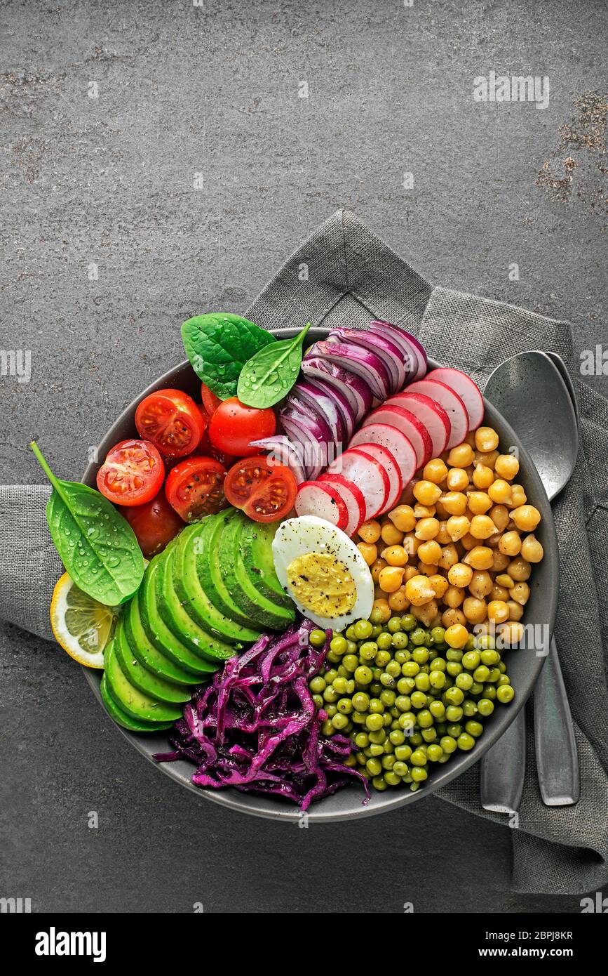 Gesunde vegane Mittagspüle. Gemüsegerichte mit Avocado, Kichererbsen, Tomaten, Rotkohl, grünen Erbsen, roten Zwiebeln und Ei Stockfoto