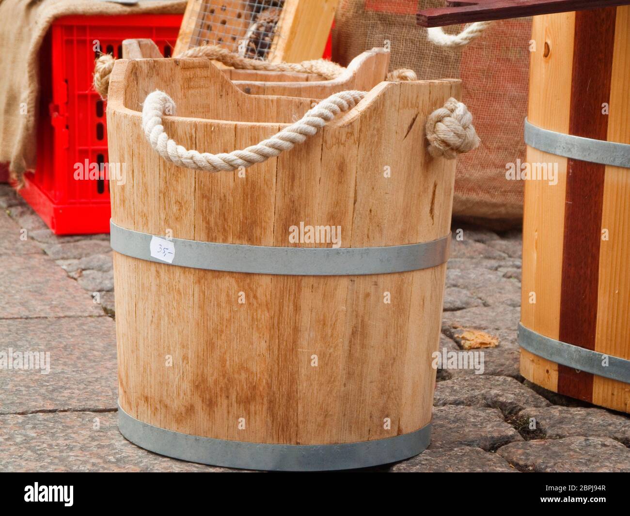 Holztrog mit zwei Stahlreifen und Hanfseil als Griff auf einem öffentlichen Flohmarkt. Stockfoto