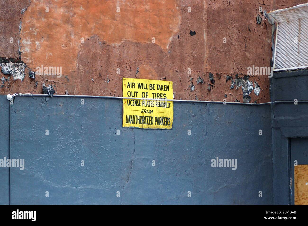 Die Luft wird aus den Reifen genommen und die Kennzeichen von nicht autorisierten Parkern entfernt. Schild an der Wand in New Yorkc City, Vereinigte Staaten von Amerika. Stockfoto