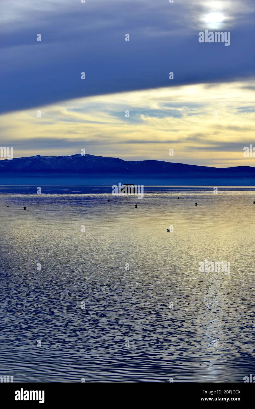 Sommeruntergang über dem ohridsee mit kleinem Boot. Stockfoto