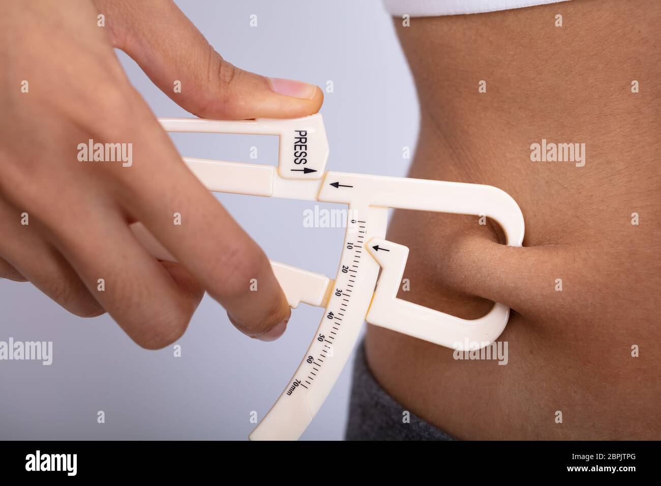 Nahaufnahme von einer Frau Hand Messen dicken Bauch mit Bremssattel auf weißem Hintergrund Stockfoto