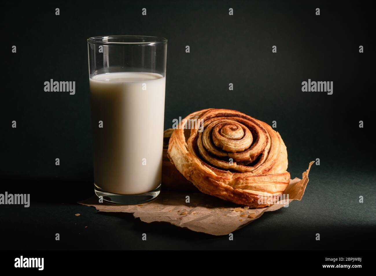 Stillleben, Zimtrollen und ein Glas Milch auf dunklem Hintergrund Stockfoto