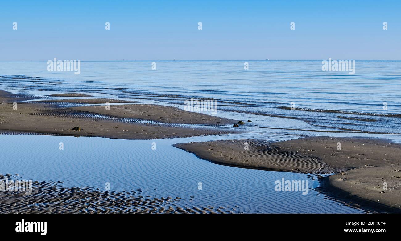 Blaues Meer im Winter in der venezianischen Lagune von Caorle, Venedig mit den typischen Texturen, die das Wasser auf dem Sand erzeugt Stockfoto