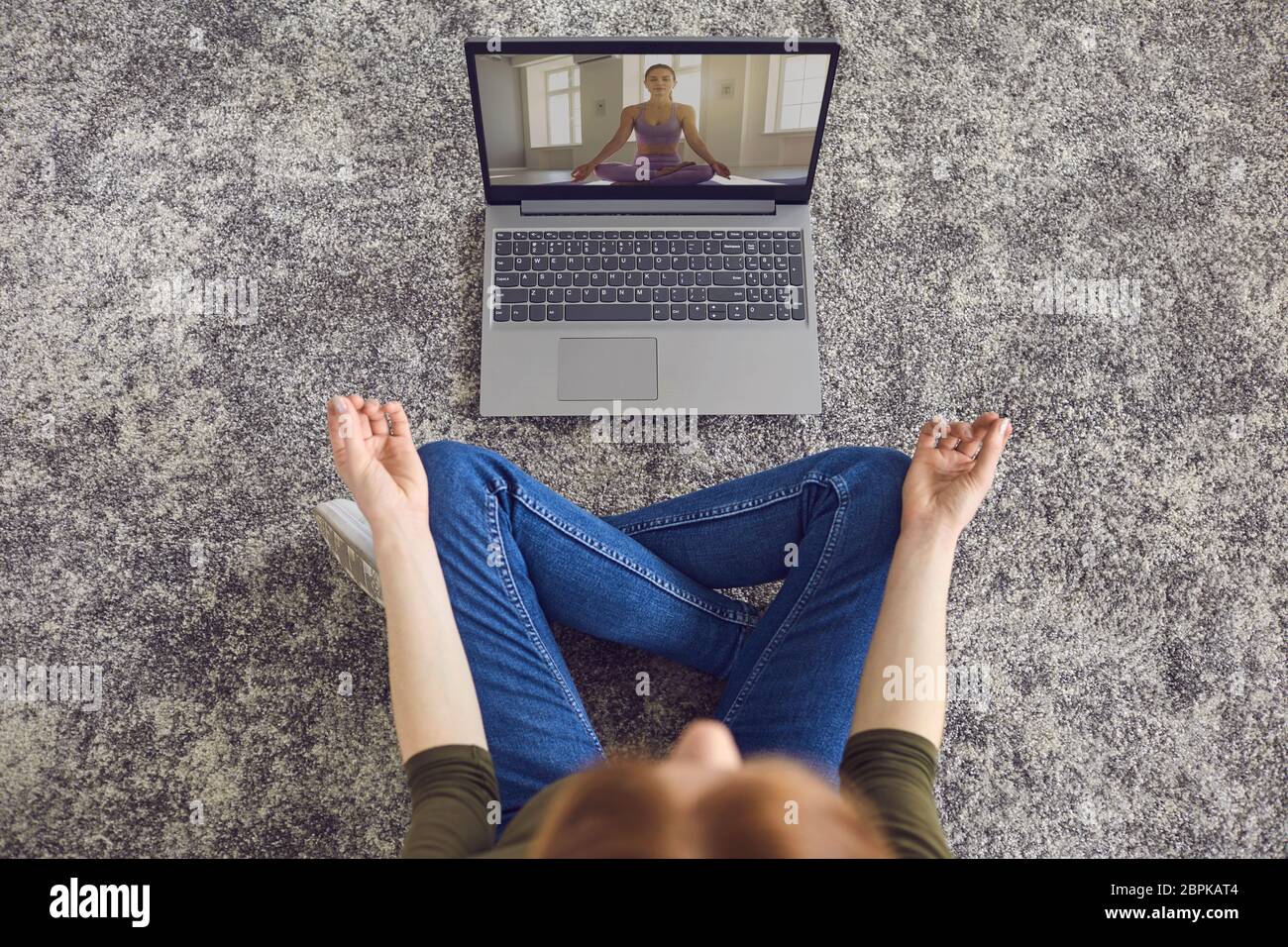 Online Yoga Meditation. Mädchen in zwangloser Kleidung praktiziert Yoga-Meditation im Zimmer. Stockfoto