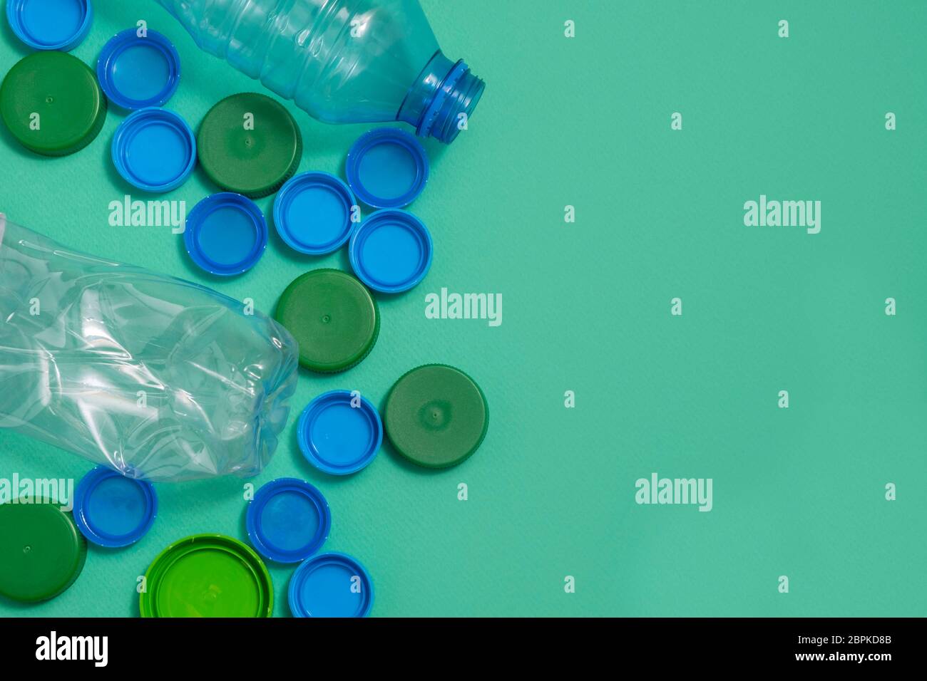Draufsicht der Plastikflaschen Kappen und Plastikflaschen auf grünem Hintergrund mit Kopierfläche Stockfoto