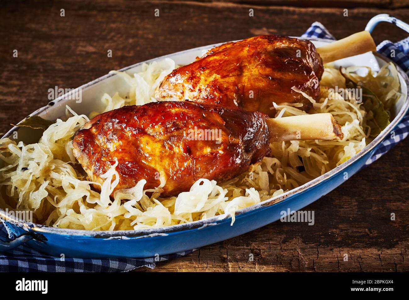 Gebratene eisbein oder Deutsch Schweinshaxen serviert auf einem Bett von zerkleinerte Kohl in ovaler Schale Stockfoto
