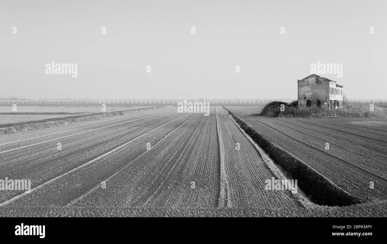 Ländliche italienische Landschaft aus Po River Lagune. gepflügten Feldern mit Perspektive. Verlassenen Lagerhalle. Bild digital geändert Stockfoto