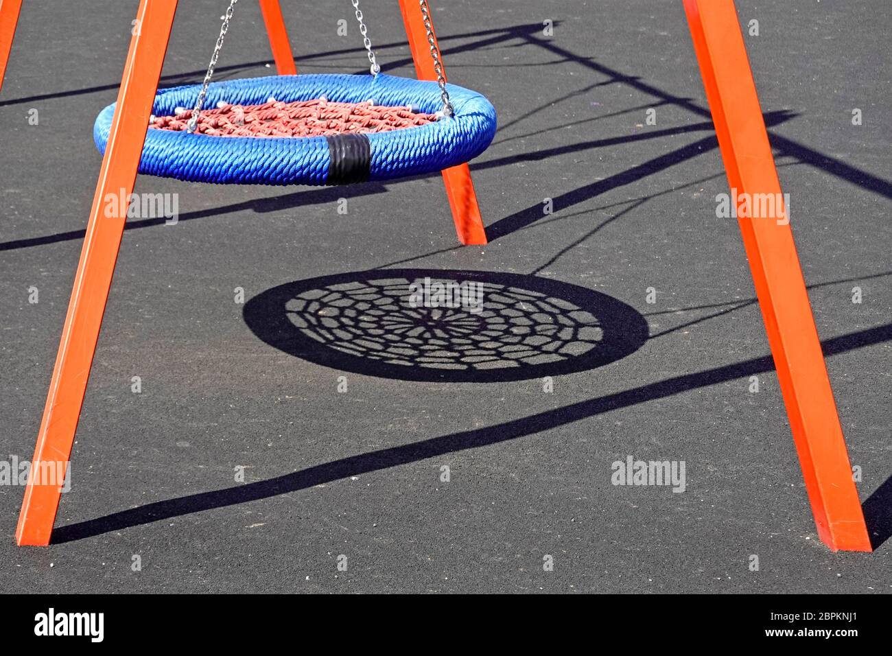 Nahaufnahme bunte abstrakte Formen und Schatten auf weichen glatten Spielplatz Oberfläche & orange Farrahmen Unterstützung Kinder spielen Schaukel England UK Stockfoto