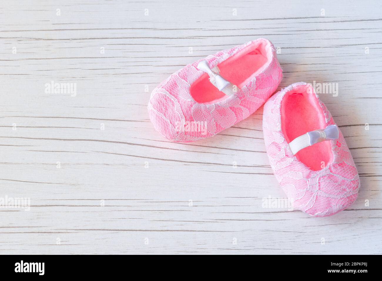 Kleine rosa Schuhe auf weißem Holzhintergrund. Wartender Baby, Babydusche. Rosa Mädchen Neugeborenen Schuhe. Mode und Kleidung für Baby Konzept. Stockfoto