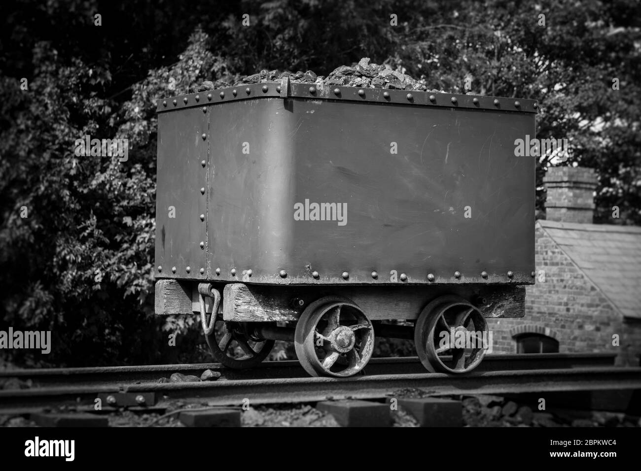 Monochrome, schwarz-weiße Nahaufnahme eines alten Kohlekraftwagens, der draußen auf Schienen isoliert ist, Black Country Living Museum, Großbritannien. Bergbau im Vintage-Stil. Stockfoto