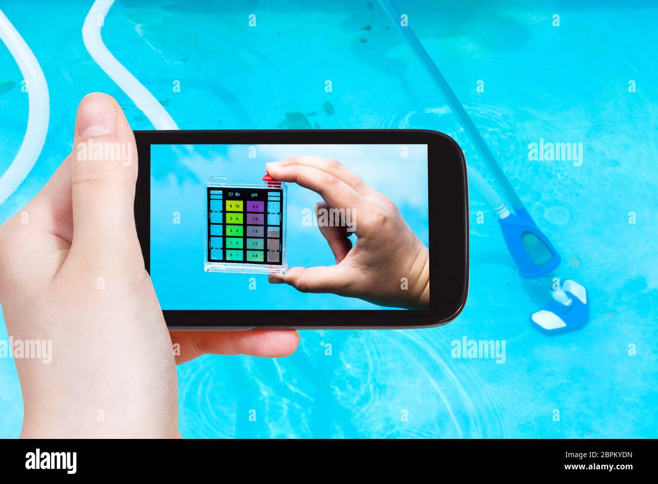 Travel Concept - touristische Fotografien einer Hand mit der pH-Indikator für den Säuregehalt des Wassers in einem Außenpool auf dem Smartphone Stockfoto