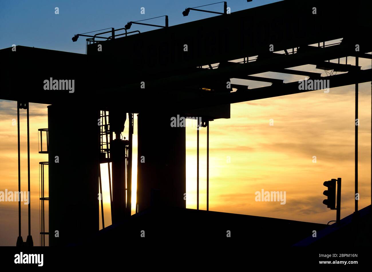 Silhoutte einer Boarding Bridge vor einer sinkenden Sonne am Hafen, Rostock, Deutschland Stockfoto