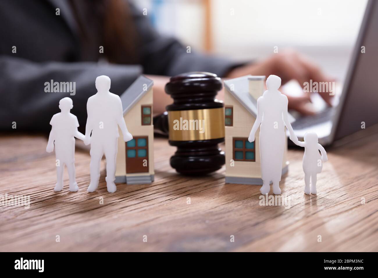 In der Nähe von Hammer zwischen Split Familie Zahlen und Haus Modell mit Business Person mit Laptop Stockfoto
