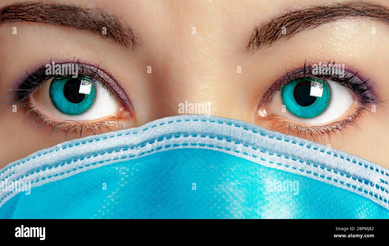 Nahaufnahme von schönen blauen Augen Frau Gesicht trägt chirurgische Maske, um sie vor krank zu schützen. Virenschutz Stockfoto