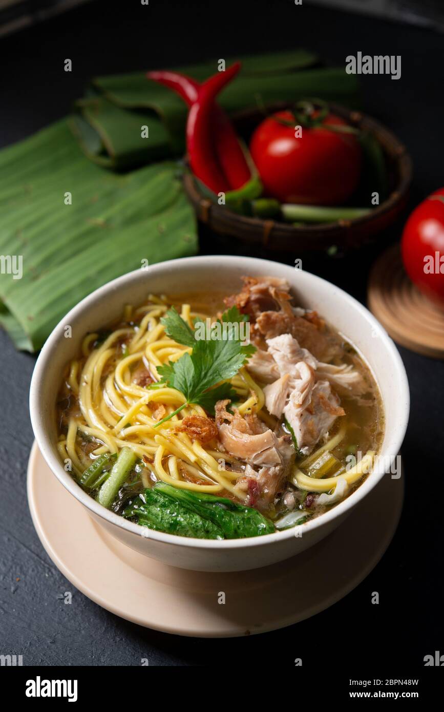 Asiatische Suppe, Nudeln und Huhn in Schüssel auf dunklem Hintergrund. Stockfoto