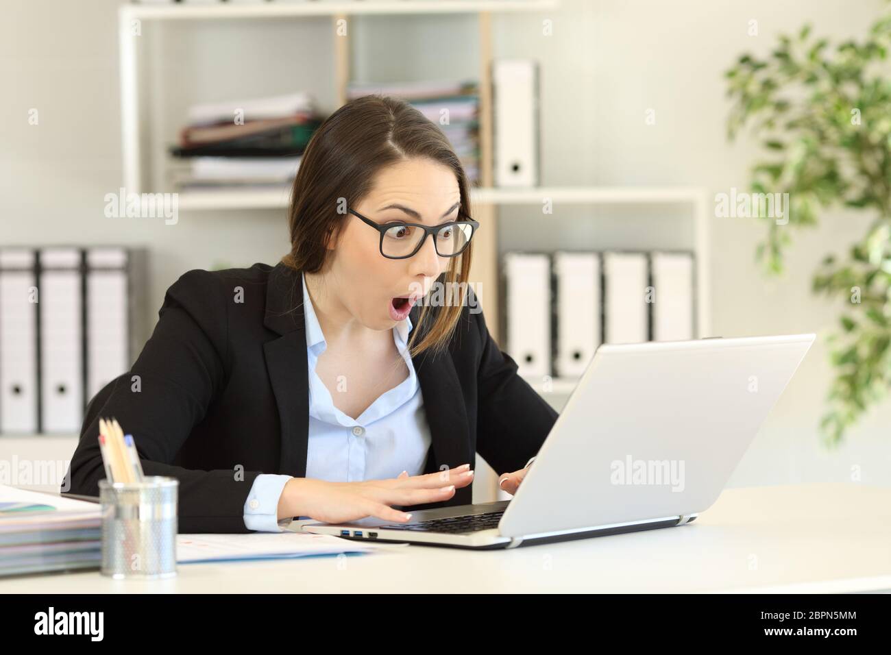 Erstaunt Büroangestellter lesen gute Nachrichten in einem Computer auf einem Desktop Stockfoto