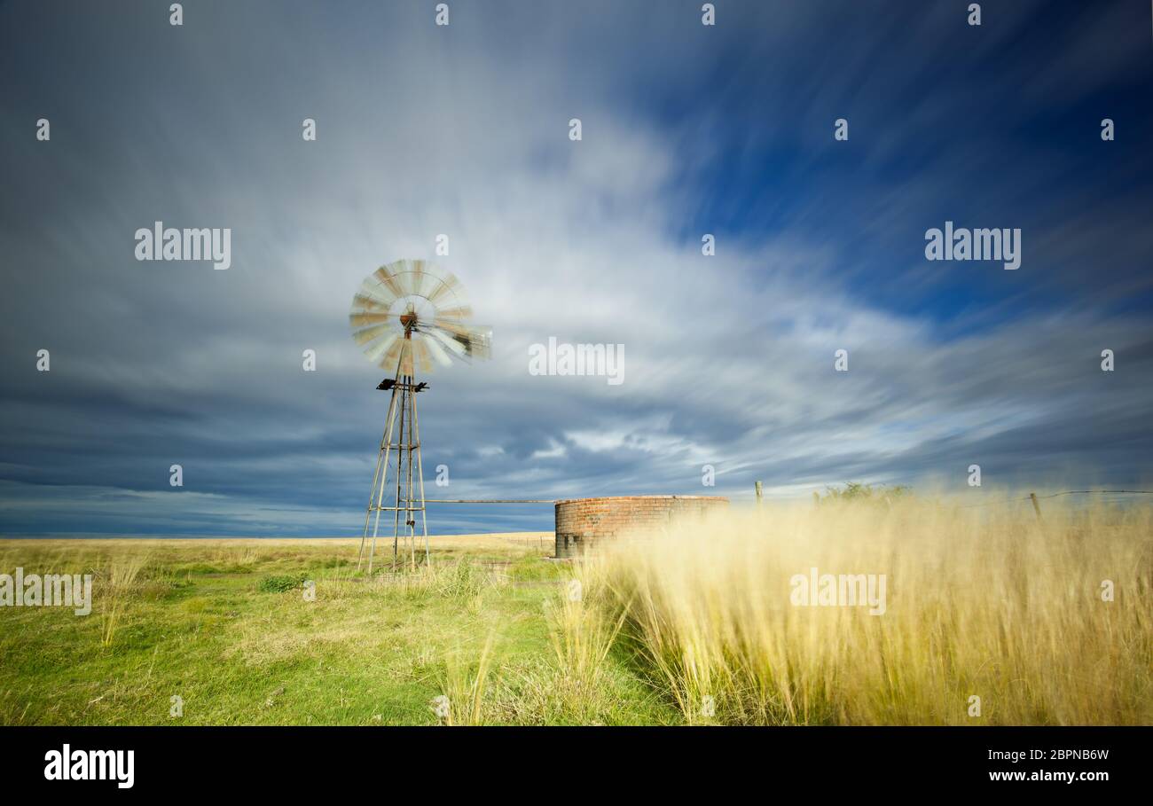 Langbelichtungs-Bild mit Windmühle und Damm und streifigen Wolken über dem Kopf Stockfoto