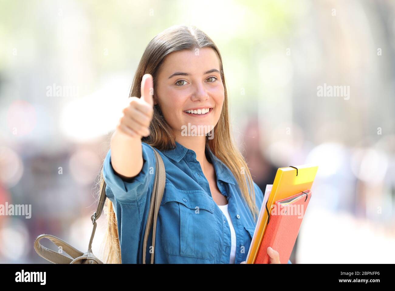 Portrait eines glücklichen Student in der Straße mit Daumen hoch, mit einem unscharfen Hintergrund Stockfoto