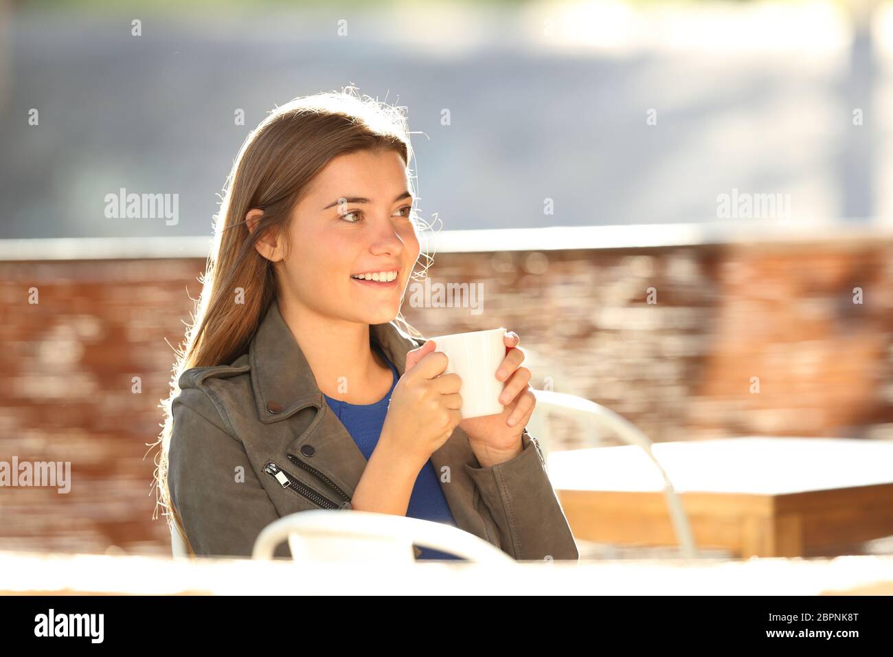 Single glücklich jugendlich Ruhen und Schauen Weg, eine Schale in einem Coffee Shop mit einem warmen Licht im Hintergrund sitzen Stockfoto