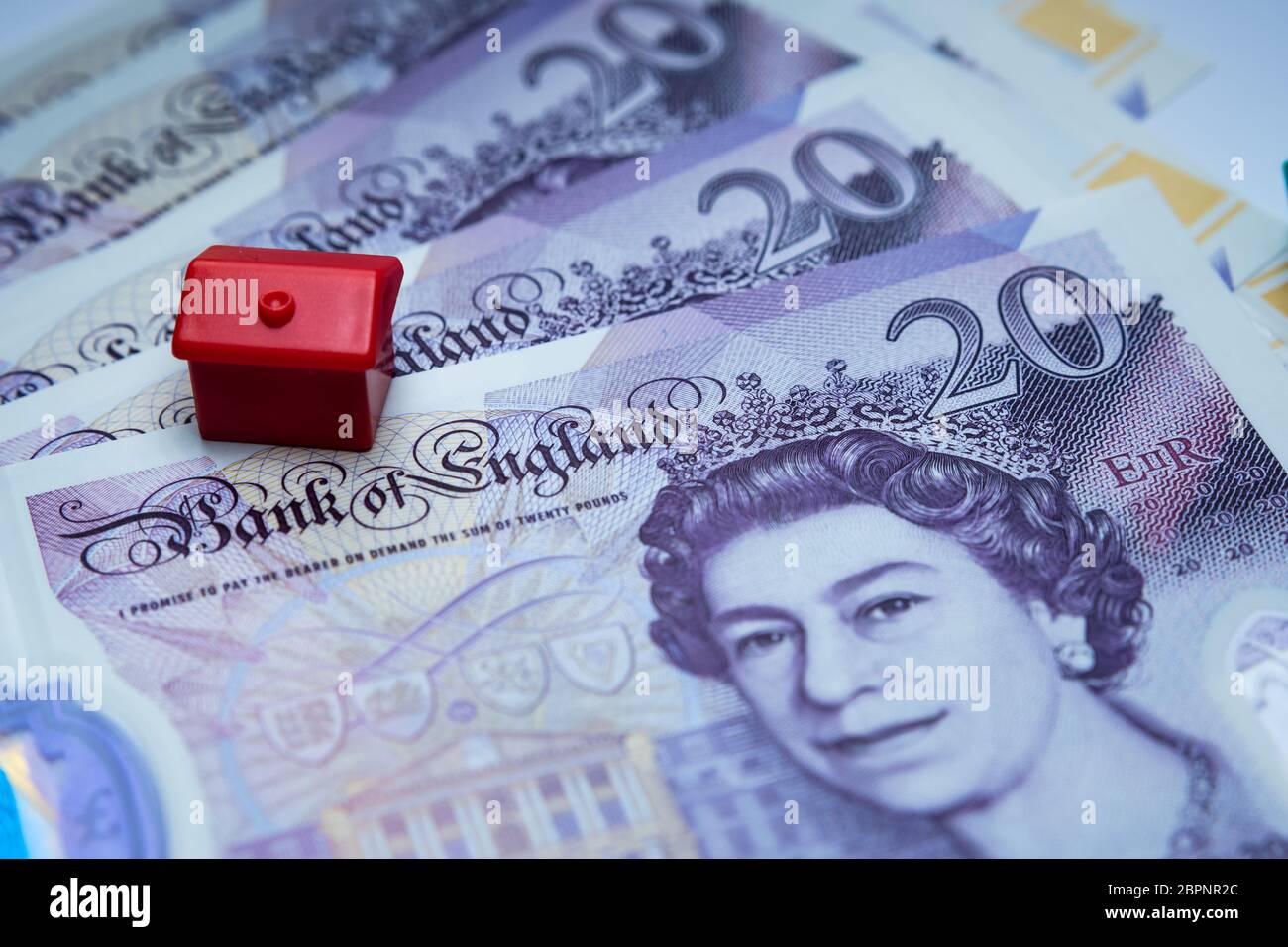 Das rote Spielzeughaus auf 20 britischen Pfund Noten platziert. Makrofoto. Konzept Bild für UK House Price Index, erste Haus, Hypothek, Immobilien oder h Stockfoto