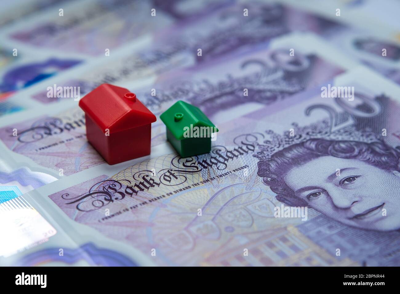 Das rote Spielzeughaus auf 20 britischen Pfund Noten platziert. Makrofoto. Konzept Bild für UK House Price Index, erste Haus, Hypothek, Immobilien oder h Stockfoto