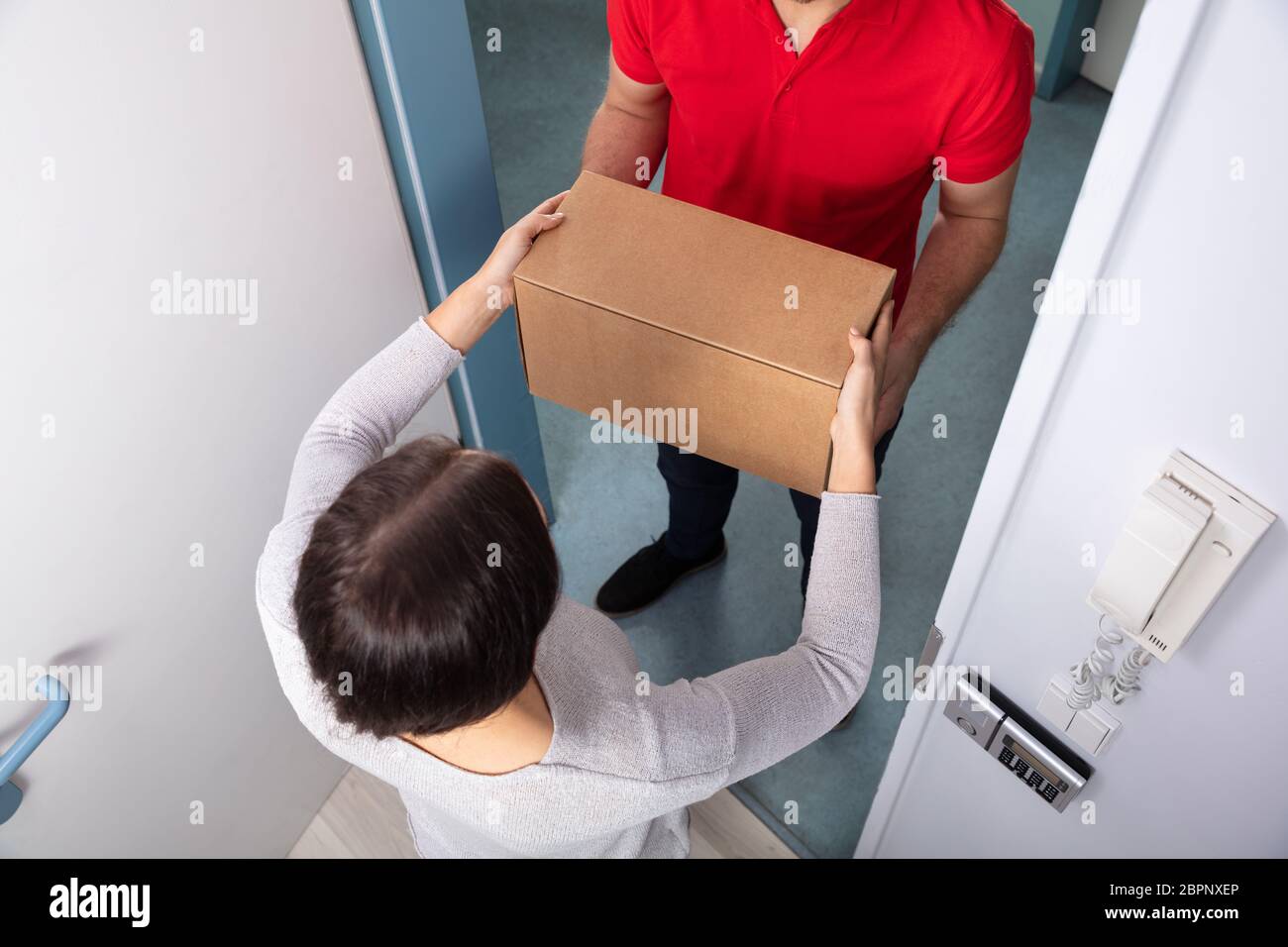 Glückliche junge Frau akzeptieren Karton ab Lieferung Mann Stockfoto