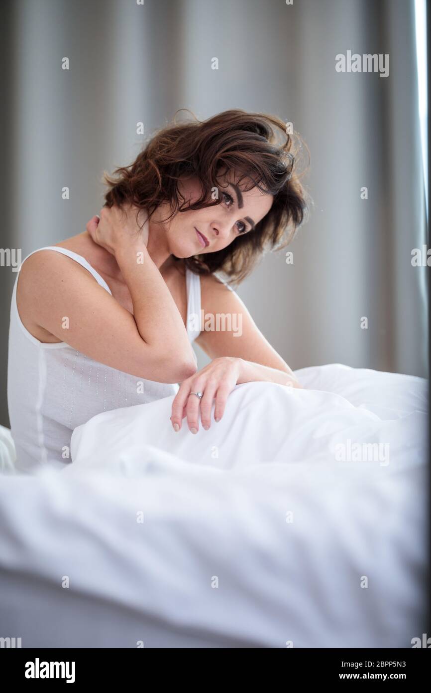 Hübsche, junge Frau mit steifen Hals, leiden unter Rückenschmerzen, in ihrem Bett am Morgen Stockfoto