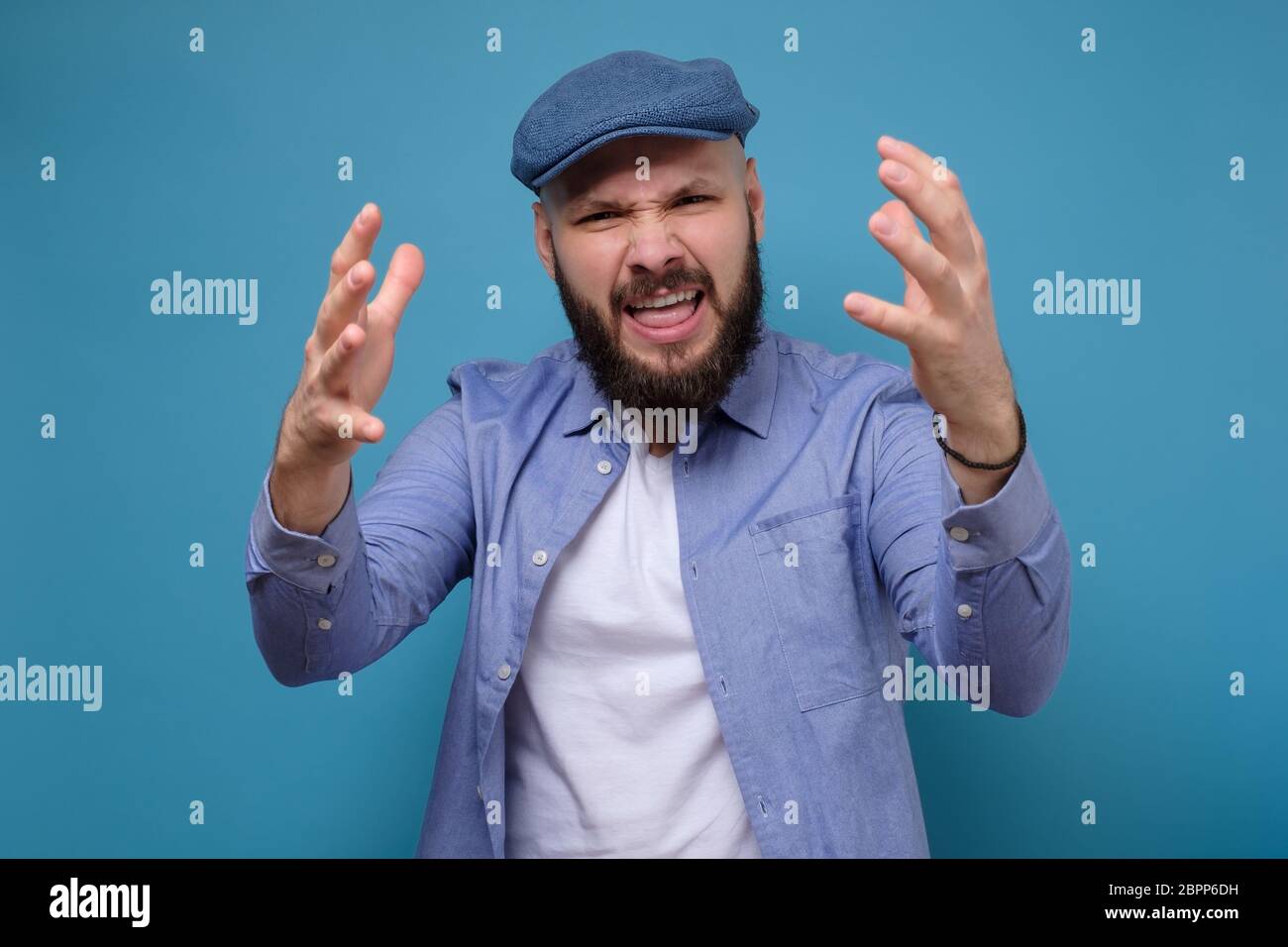 Argumentieren, argumentieren Konzept. Emotional überrascht Mann Streit mit seiner Frau. Studio auf blauer Wand gedreht. Stockfoto