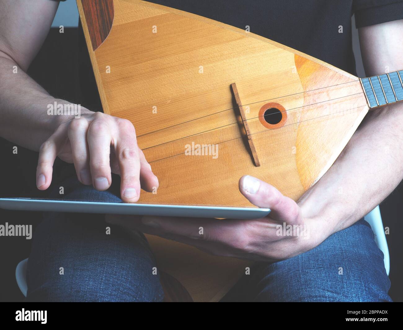 Junge Musiker mit einer Verwendung eines Tablet Computer Balalaika Stockfoto