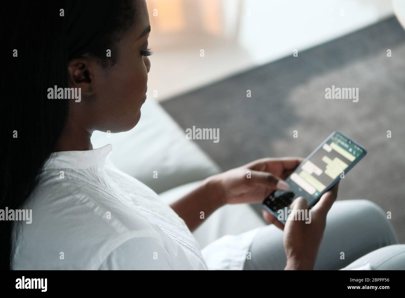 Schwarze Frau, Die Mobiltelefon Für Sms Verwendet Stockfoto