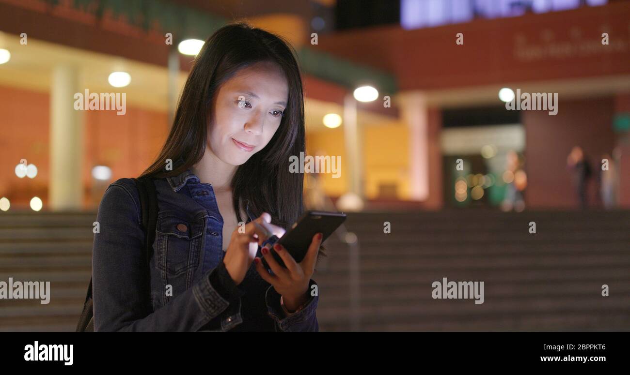 Frau Blick auf Smart Phone in der Stadt bei Nacht Stockfoto