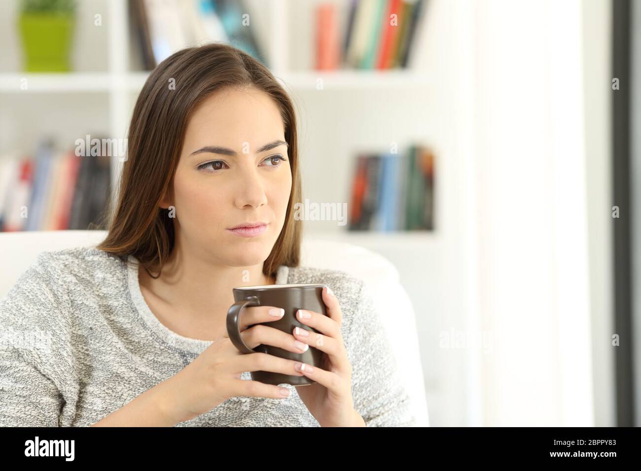 Traurige Frau wundern, weg schauen sitzen auf einer Couch im Wohnzimmer zu Hause Stockfoto