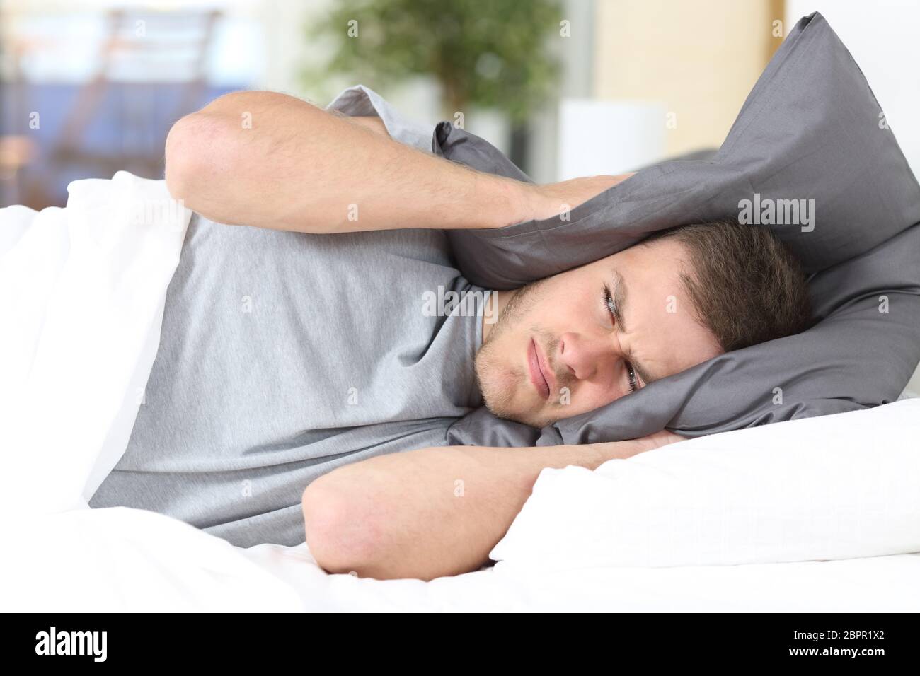 Ein Mann versucht zu schlafen für Ohren zur Vermeidung von Nachbar Lärm zu Hause oder im hotel Stockfoto