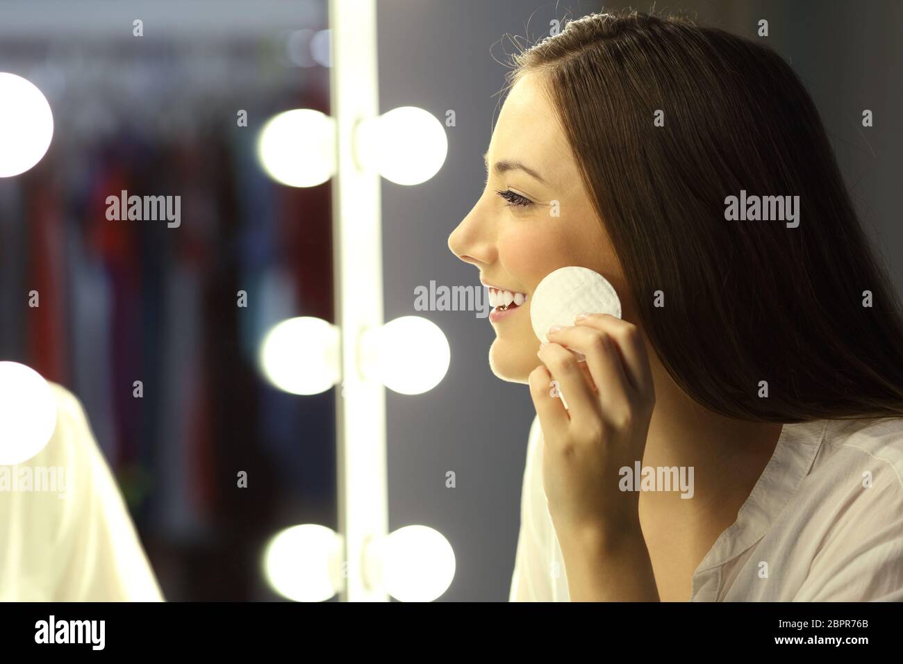 Seitenansicht einer Frau entfernen Make-up mit einem Remover vor einem Spiegel Stockfoto