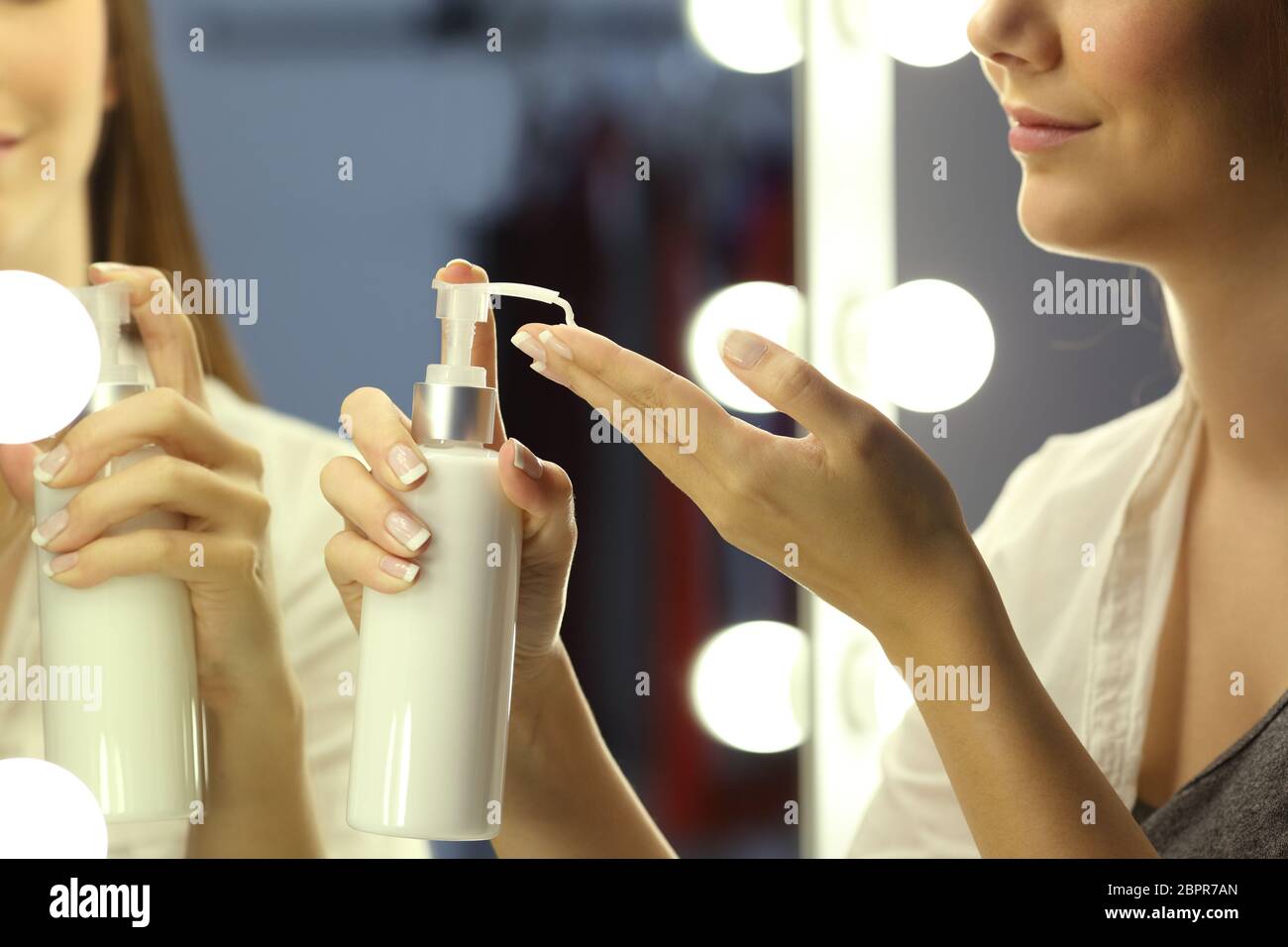 Porträt einer Frau, die Anwendung der Feuchtigkeitscreme Creme auf Hände vor Make up Spiegel Stockfoto