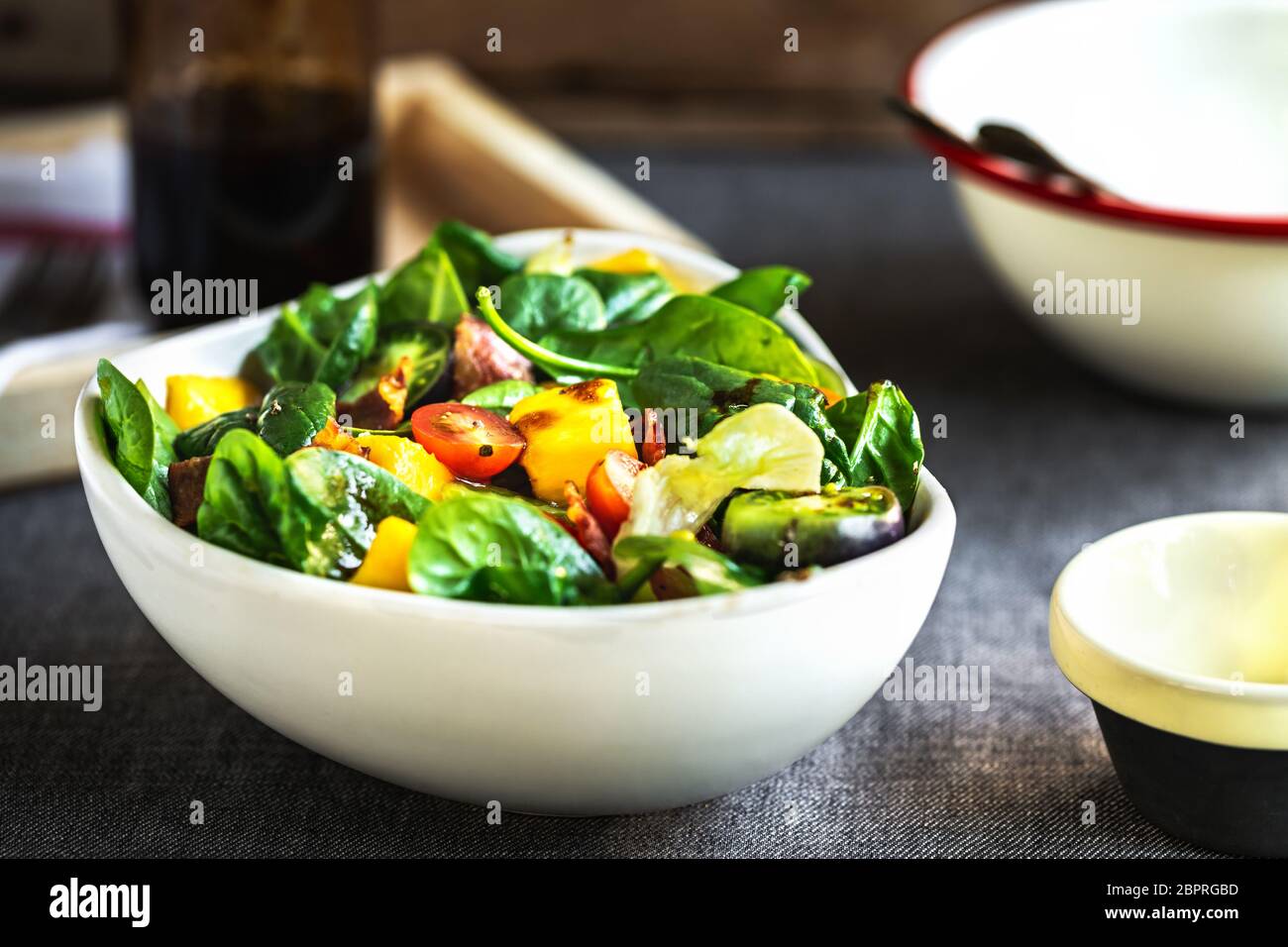 Mango mit Speck Cherry Tomaten und Spinat Salat mit Balsamico Dressing Stockfoto