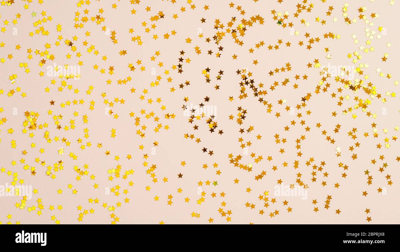 Goldene Sterne in Form von Konfetti auf beigefarbenem Hintergrund Draufsicht. Stockfoto