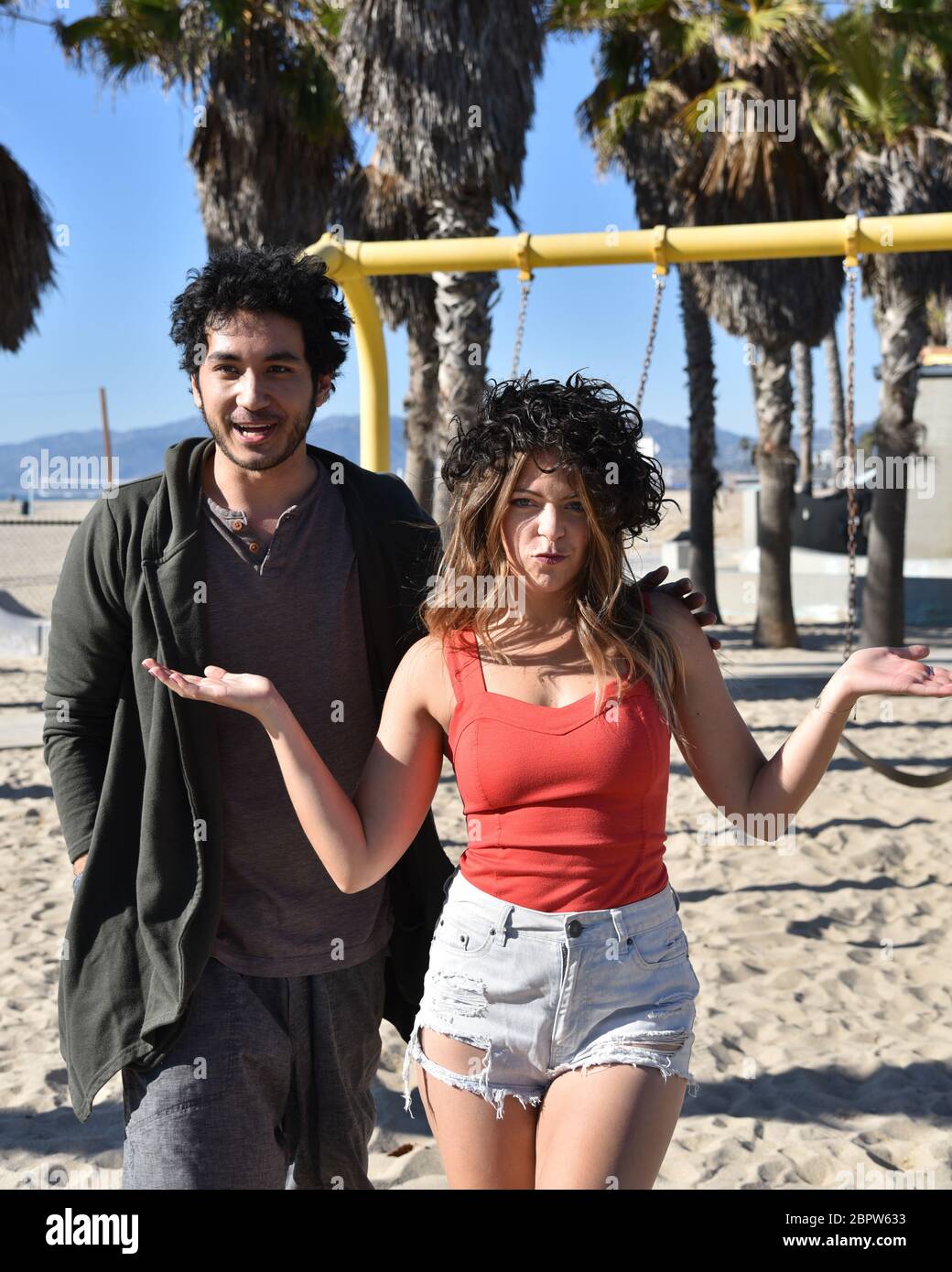 Ein glückliches junges Paar, das sich am Strand mit einer Perücke dumm verhält Stockfoto