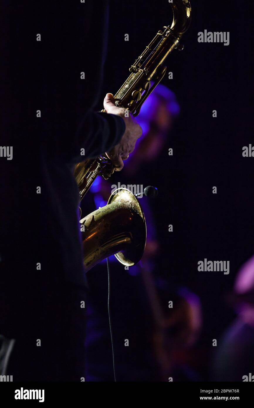 Details eines beleuchteten Saxophons mit der Hand des Musikers während eines Konzerts Stockfoto