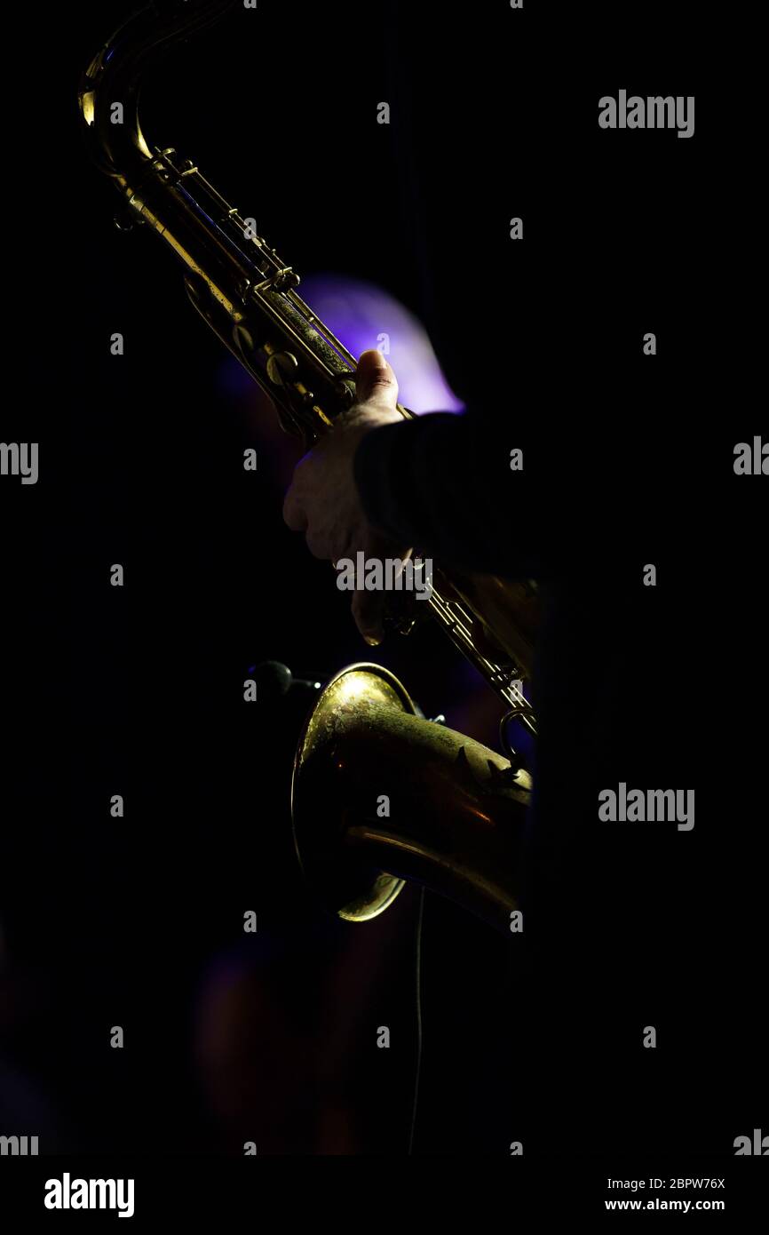 Details eines beleuchteten Saxophons mit der Hand des Musikers während eines Konzerts Stockfoto