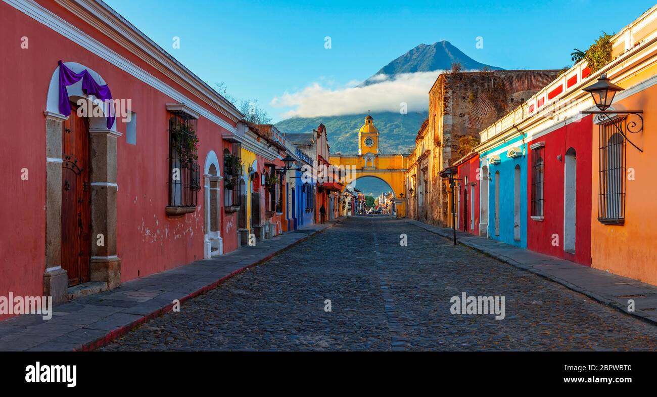 Panorama Sonnenaufgang in der Hauptstraße von Antigua City mit dem Santa Catalina Arch und dem Vulkan Agua, Guatemala. Stockfoto