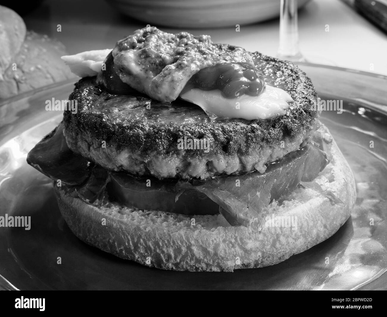 Leckerer Rinderburger mit Käse, Ketchup und Senf. Gourmet-Essen in schwarz und weiß Stockfoto