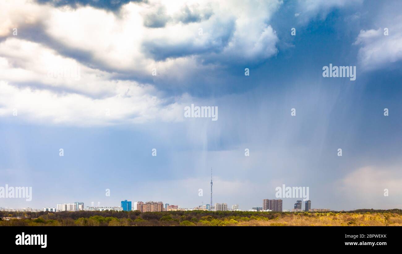 Panoramablick auf Regen und Regenwolken über Stadt und Park im Frühjahr Stockfoto